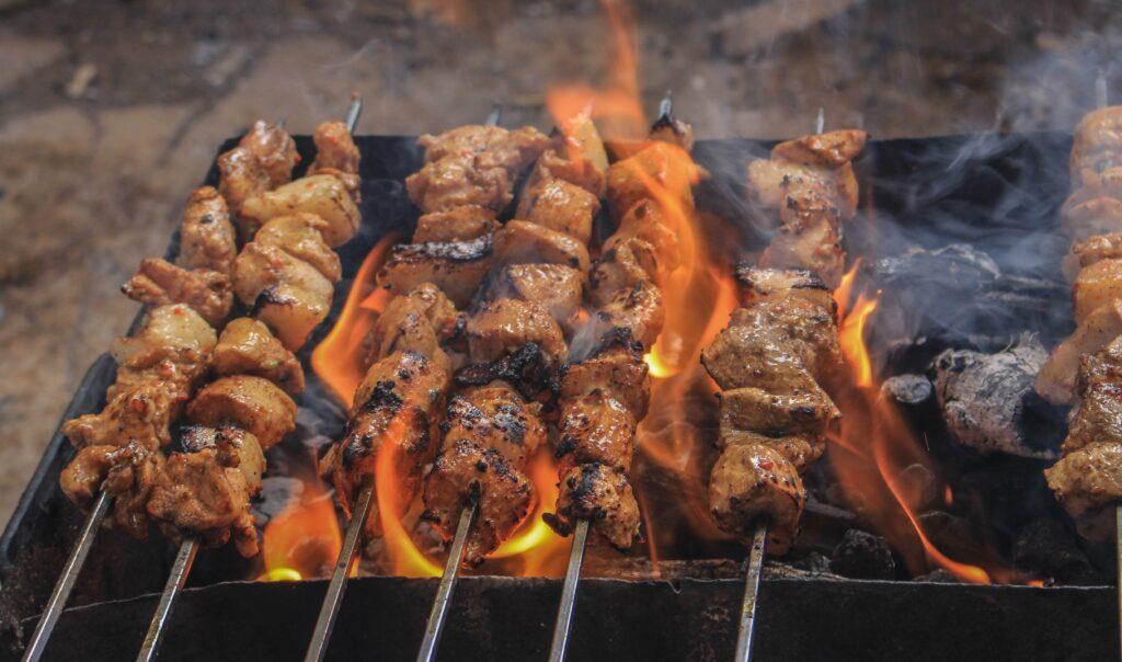 Chicken cooking on a grill with fire coming through.