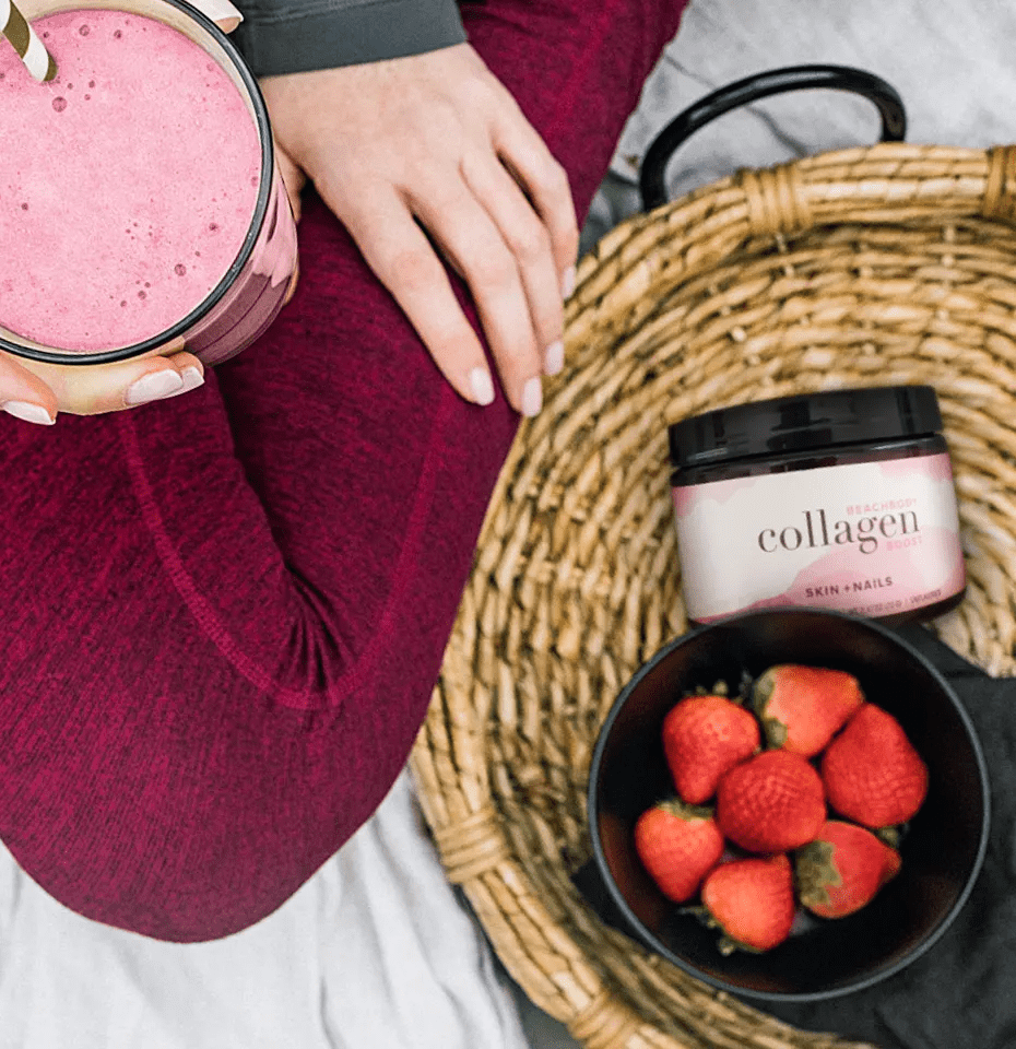 a picture of a woman sitting with a shake, collagen boost from Beachbody and strawberries