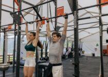 man and a woman holding on to a bar abut to do a pull up