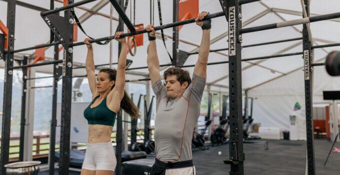 man and a woman holding on to a bar abut to do a pull up