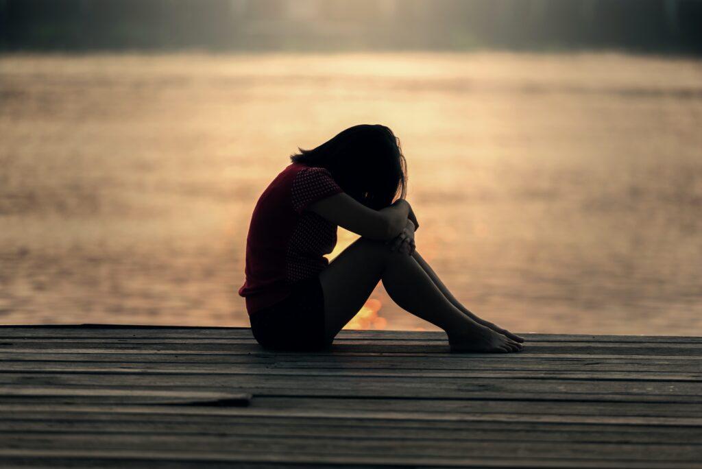 depressed woman sitting by the sea